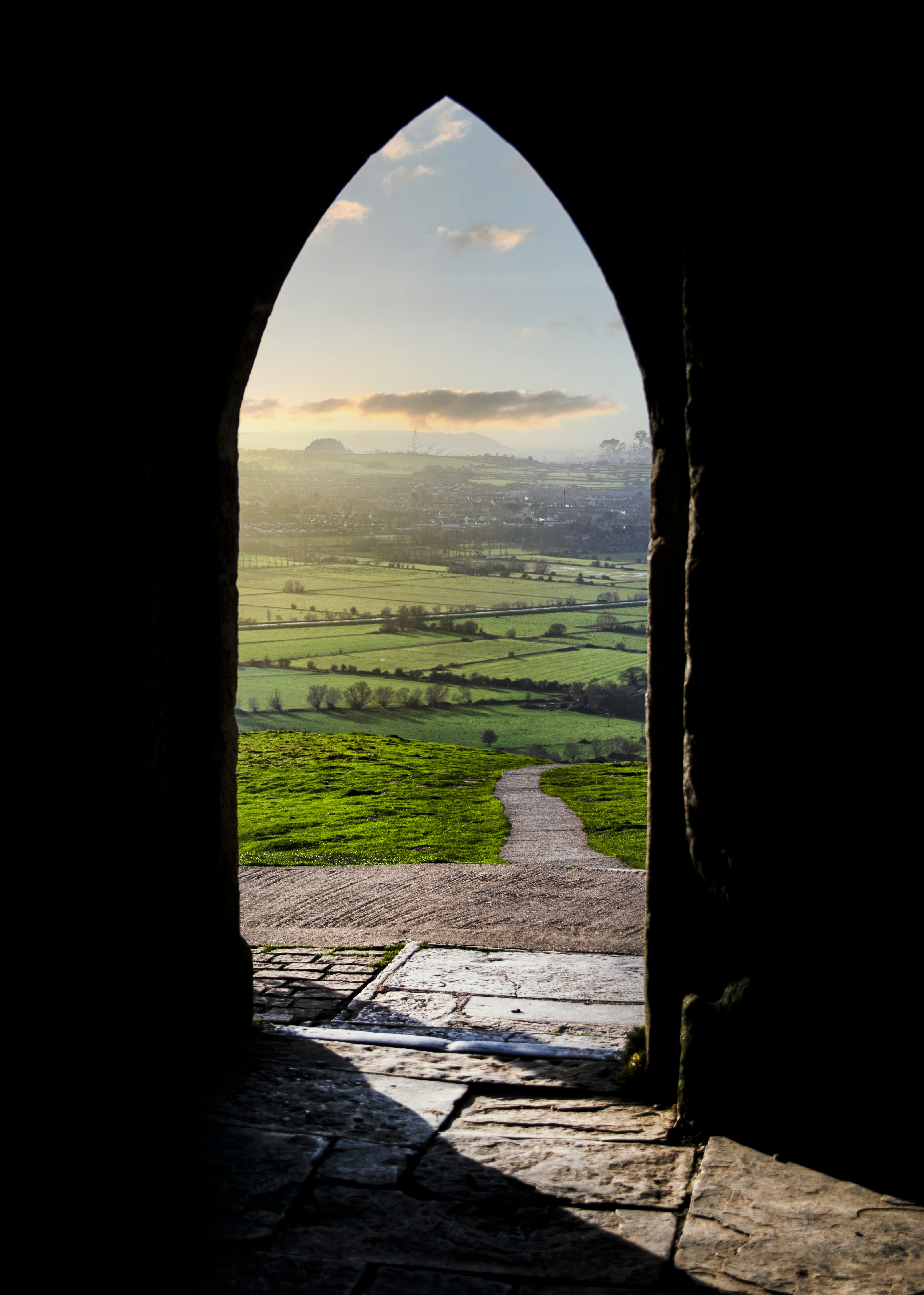 A sunlit path seen through a stone archway